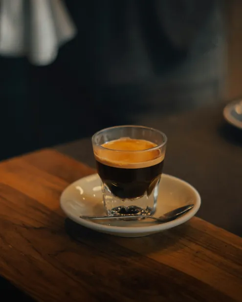 Espresso într-un pahar mic de sticlă, pe o masă de lemn
