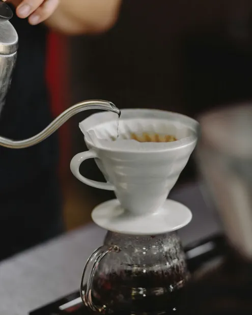 Apă turnată din ibric peste un filtru V60 alb